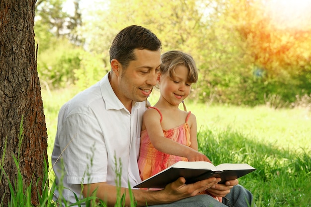 Jonge vader met een kleine dochter die de bijbel leest