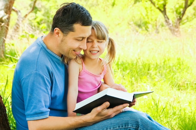 Jonge vader met een kleine dochter die de bijbel leest