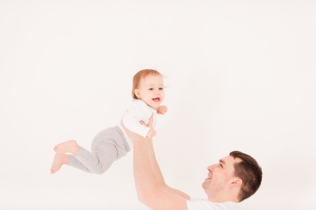 Jonge vader tilt zijn kleine babymeisje op, geïsoleerd op wit