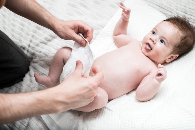 Jonge vader verandert de luier voor zijn baby. Witte achtergrond. Detailopname. Pasgeboren zorgconcept.