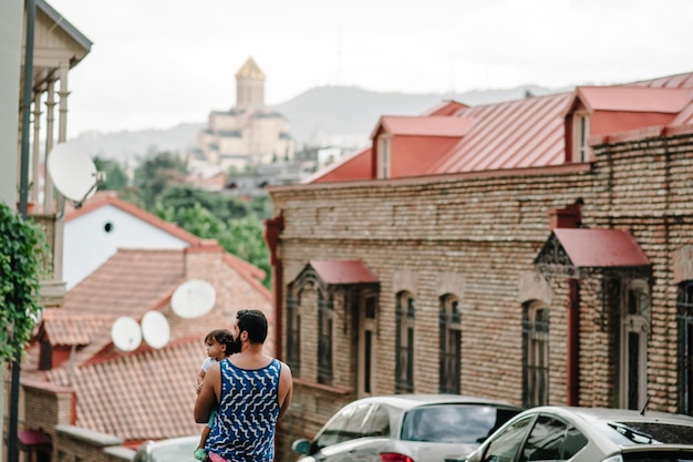 Jonge vader wandelen met dochtertje buiten op straten in de stad tbilisi in de hoofdstad van georgië op zonnige lentedag vader en meisje reizen op excursie in de oude stad