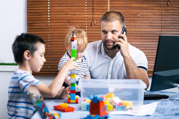 Jonge vader zakenman ouder onderbreekt door haar kinderen zonen tijdens het werken in huis.