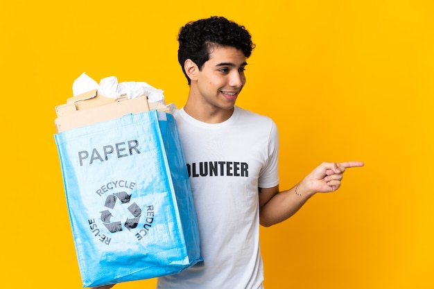 Jonge Venezolaanse man die een recyclingzak vol papier vasthoudt om de wijzende vinger opzij te recyclen