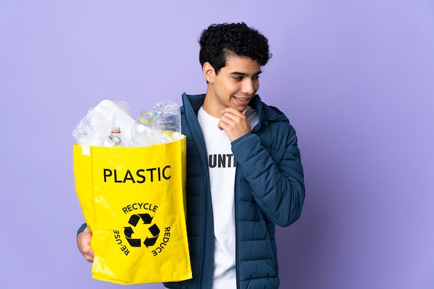 Jonge Venezolaanse man met een zak vol plastic flessen opzij kijken en glimlachen