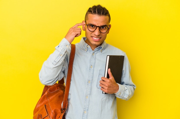 Jonge venezolaanse student man geïsoleerd op gele achtergrond met een gebaar van teleurstelling met wijsvinger.