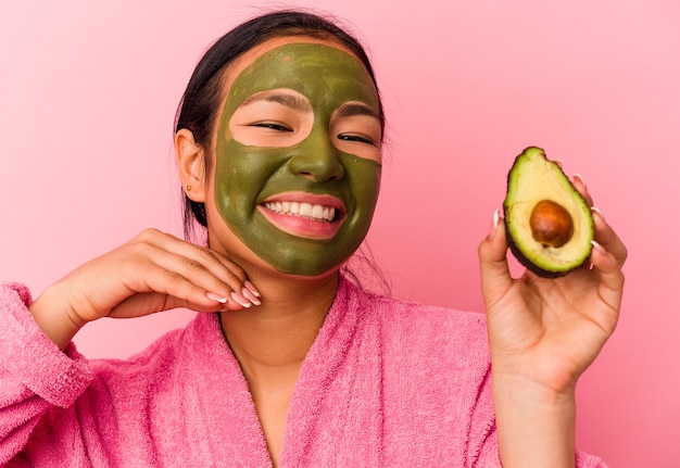 Jonge Venezolaanse vrouw die een gezichtsmasker draagt dat op roze achtergrond wordt geïsoleerd