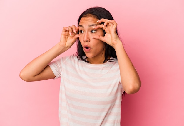 Jonge Venezolaanse vrouw die op roze achtergrond wordt geïsoleerd die ogen open houdt om een succeskans te vinden.