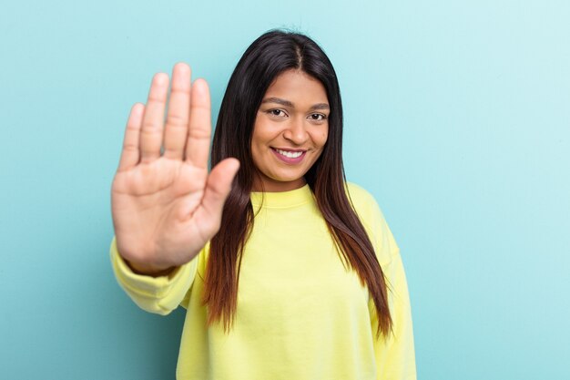 Jonge Venezolaanse vrouw geïsoleerd op blauwe achtergrond glimlachend vrolijk met nummer vijf met vingers.