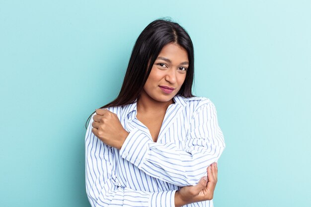 Jonge Venezolaanse vrouw geïsoleerd op blauwe achtergrond masseren elleboog, lijden na een slechte beweging.