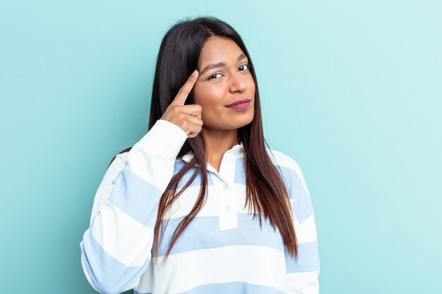 Jonge Venezolaanse vrouw geïsoleerd op blauwe achtergrond wijzende tempel met vinger, denken, gericht op een taak.