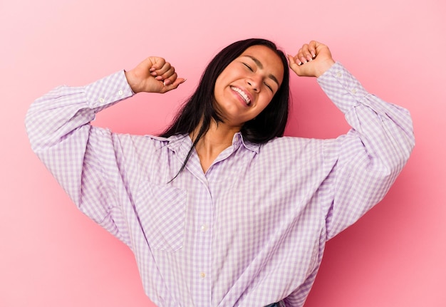 Jonge Venezolaanse vrouw geïsoleerd op een roze achtergrond die een speciale dag viert, springt en steekt de armen op met energie