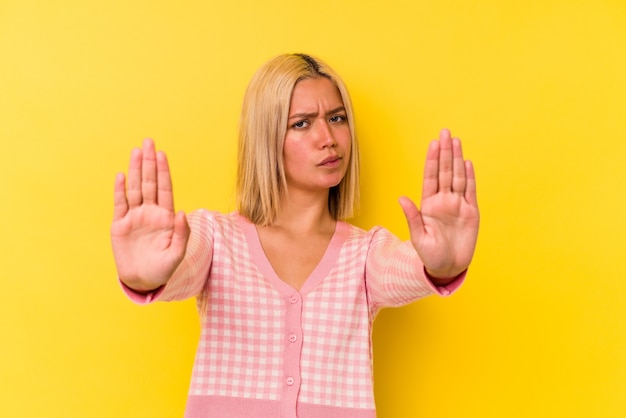 Jonge Venezolaanse vrouw geïsoleerd op gele achtergrond permanent met uitgestrekte hand weergegeven: stopbord, voorkomen dat u.