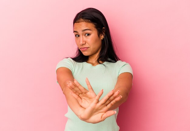 Jonge Venezolaanse vrouw geïsoleerd op roze achtergrond permanent met uitgestrekte hand weergegeven: stopbord, voorkomen dat u.