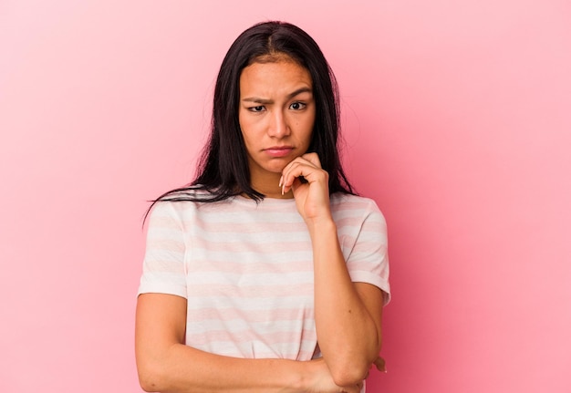 Jonge Venezolaanse vrouw geïsoleerd op roze achtergrond verdacht onzeker die jou onderzoekt