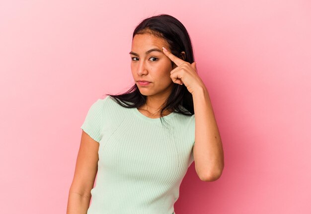 Jonge Venezolaanse vrouw geïsoleerd op roze achtergrond wijzende tempel met vinger denken gericht op een taak