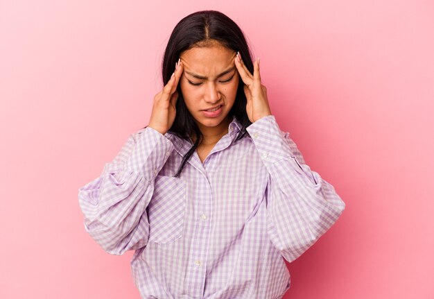 Jonge Venezolaanse vrouw geïsoleerd op roze muur met hoofdpijn, aanraken van de voorkant van het gezicht.