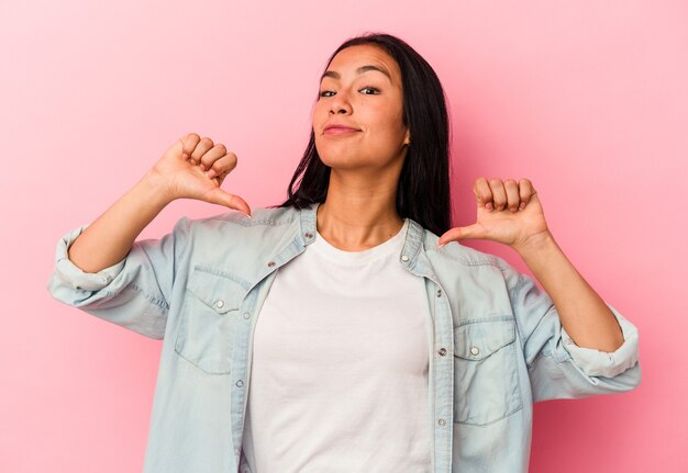 Jonge Venezolaanse vrouw geïsoleerd op roze muur voelt zich trots en zelfverzekerd, voorbeeld om te volgen.