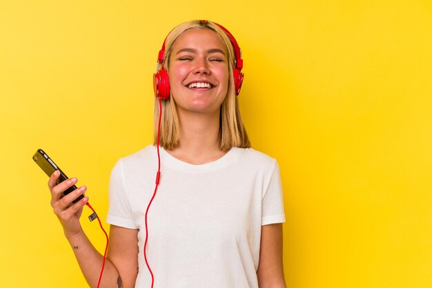 Jonge Venezolaanse vrouw luisteren muziek geïsoleerd op gele achtergrond