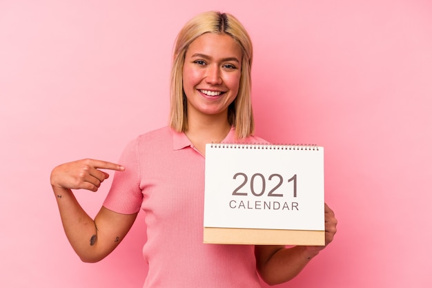 Foto jonge venezolaanse vrouw met een kalender geïsoleerd op een roze achtergrond persoon met de hand wijzend naar een shirt kopie ruimte, trots en zelfverzekerd