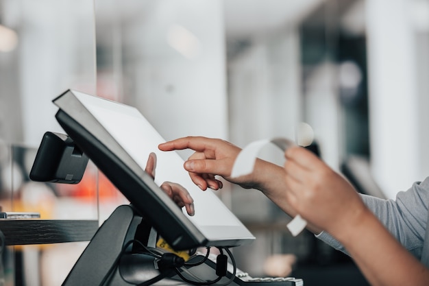 Foto jonge verkoopster die procesbetaling doet op het touchscreen pos, verkoop in de kassa telt, financieel concept