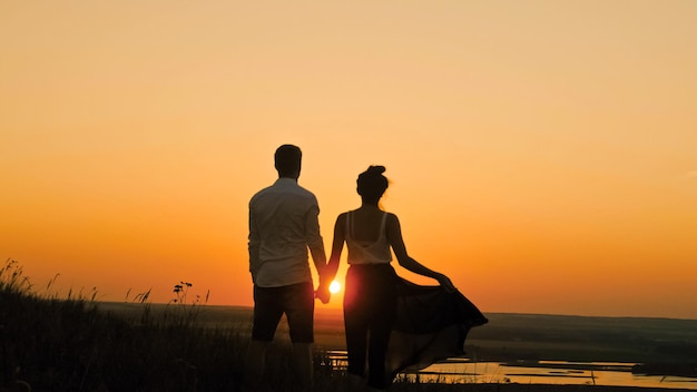 Jonge verliefde paar dappere man en mooi meisje in de schemering silhouet op zoek naar zon