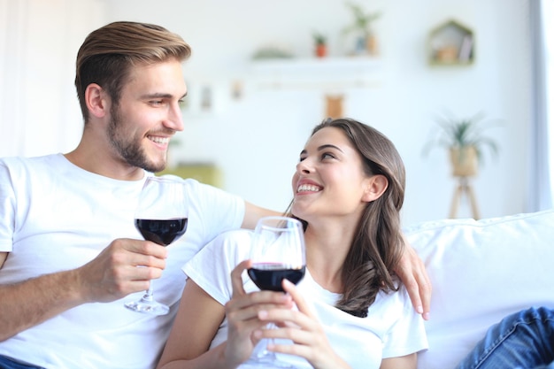 Jonge verliefde paar drinken van een glas rode wijn in hun woonkamer.