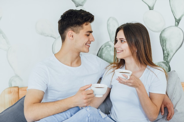 Jonge verliefde paar koffie drinken in bed en praten