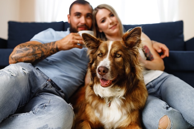 Jonge verliefde paar ontspannen in de woonkamer met hun hond huisdier