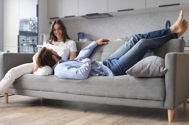 Jonge verliefde paar ontspannen op de bank samen man liggend op de benen van de vrouw rustend op de bank concept van het vastleggen van een gelukkig moment