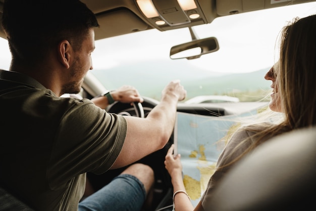 Jonge verliefde paar op een road trip met behulp van kaart in een auto, close-up