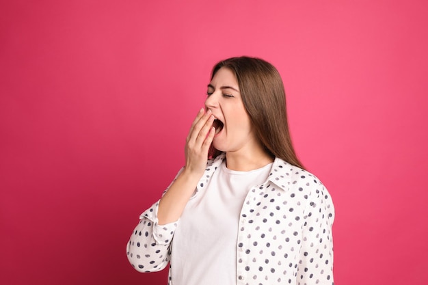 Jonge vermoeide vrouw geeuwen op roze achtergrond