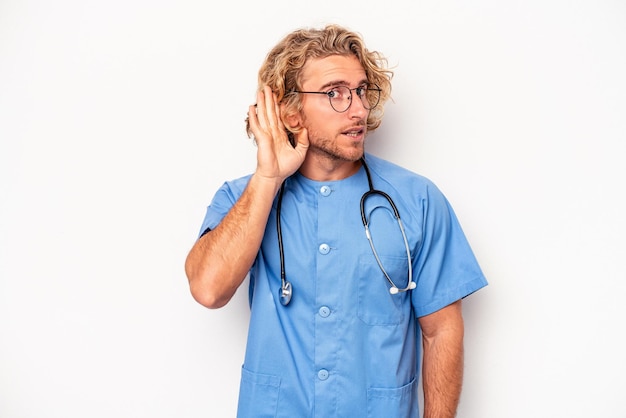 Foto jonge verpleegster blanke man geïsoleerd op een witte achtergrond probeert te luisteren naar een roddel.