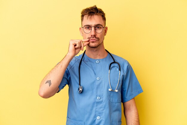 Jonge verpleegster blanke man geïsoleerd op gele achtergrond met vingers op lippen houden een geheim.