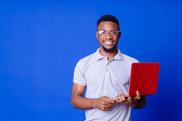 Jonge verrast Afro-Amerikaanse man permanent en met behulp van laptopcomputer