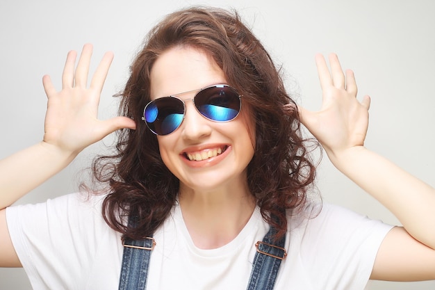 Jonge verraste vrouw die zonnebril draagt. Emotioneel portret.