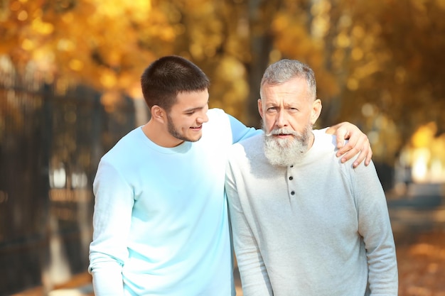 Jonge verzorger wandelen met senior man in park