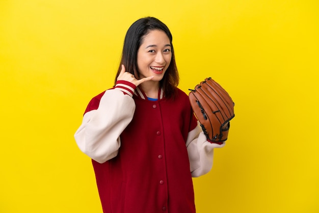 Jonge Vietnamese speler vrouw met honkbal handschoen geïsoleerd op gele achtergrond telefoon gebaar maken Bel me terug teken