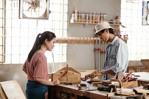 Jonge Vietnamese timmerlieden werken met houten planken en blokken op de werkbank