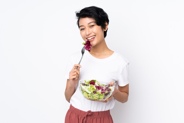 Jonge vietnamese vrouw die met kort haar een salade over geïsoleerd houdt