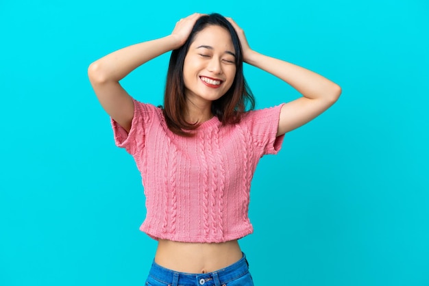 Jonge Vietnamese vrouw geïsoleerd op blauwe achtergrond lachen