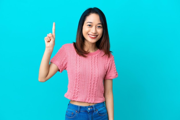 Jonge Vietnamese vrouw geïsoleerd op een blauwe achtergrond die een geweldig idee benadrukt