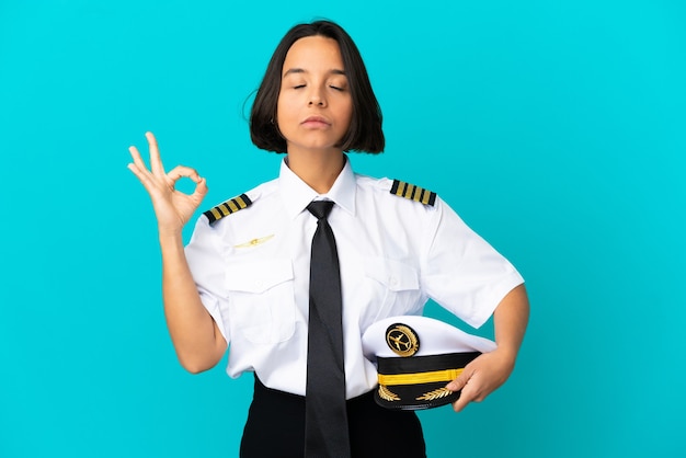 Jonge vliegtuigpiloot over geïsoleerde blauwe achtergrond in zen pose