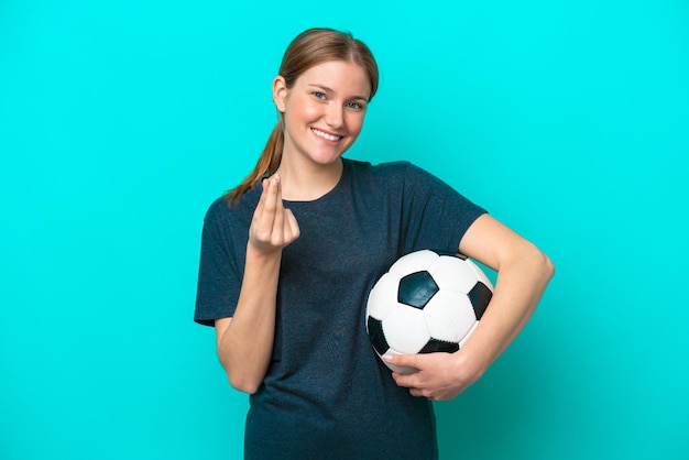 Jonge voetballer vrouw geïsoleerd op blauwe achtergrond geld gebaar maken