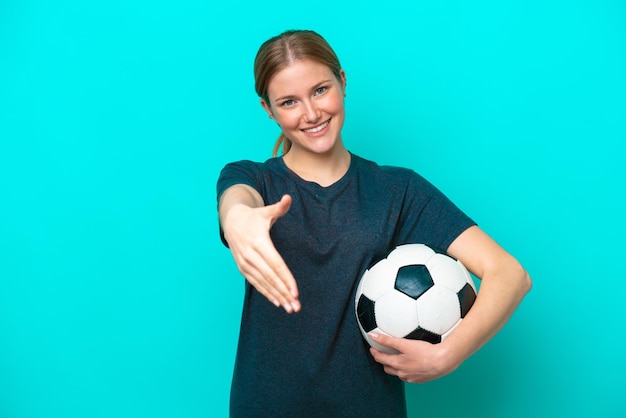 Jonge voetballer vrouw geïsoleerd op blauwe achtergrond handen schudden voor het sluiten van een goede deal