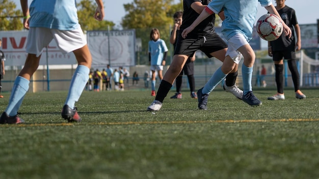 Jonge voetballers rennen snel en schoppen witte voetbalbal Jeugdvoetballers strijden in toernooiwedstrijd Voetbalatleet schoppen bal Schoolsportcompetitie