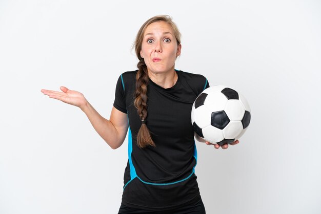 Jonge voetballervrouw die op witte achtergrond wordt geïsoleerd die twijfels heeft terwijl het opheffen van handen