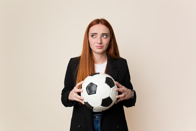 Jonge voetbaltrainer vrouw die een voetbal geïsoleerd houdt