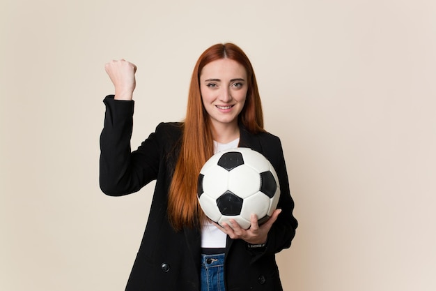 Jonge voetbaltrainer vrouw die een voetbal geïsoleerd houdt