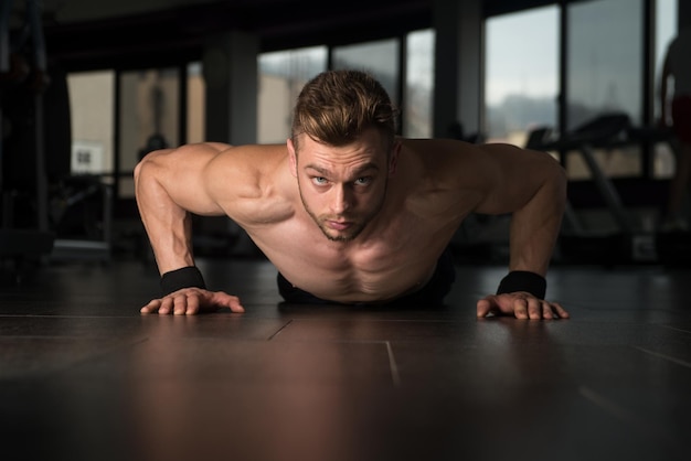 Jonge volwassen atleet die push-ups doet als onderdeel van bodybuilding-training