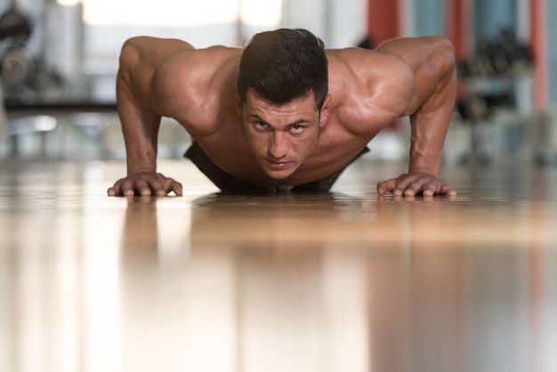 Jonge volwassen atleet die push-ups doet als onderdeel van bodybuilding-training